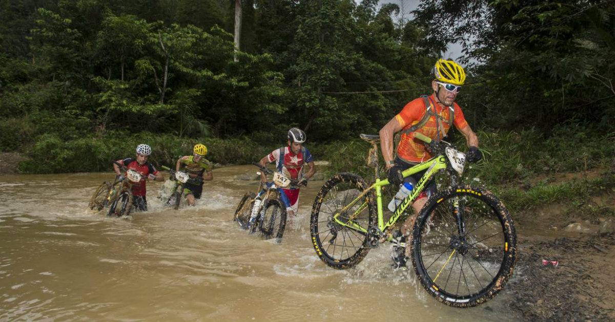 Varios ciclistas cruzan un río de la selva cubana con la bici a cuestas © 