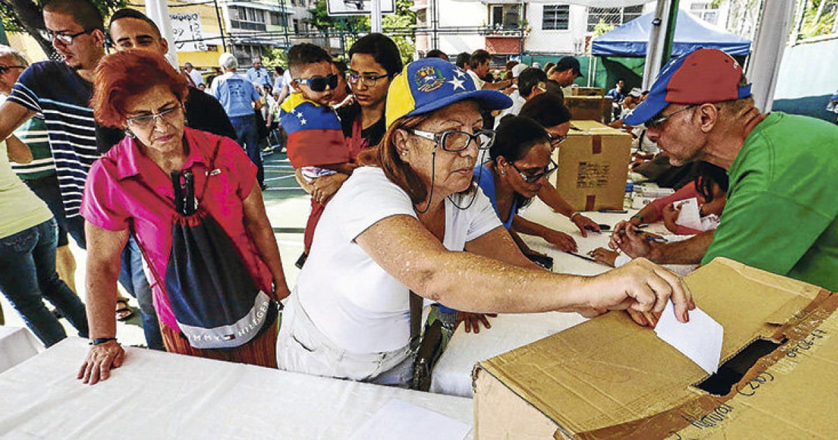 Venezolanos depositando su voto en una caja de cartón © La Tercera